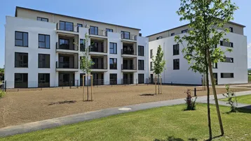 Moderne Wohngebäude mit weißer Fassade und Balkonen in einer neuen Wohnanlage.