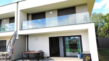 Moderne Doppelhaushälfte mit großer Terrasse, Garten und Balkon, ideal für entspannte Stunden im Freien.