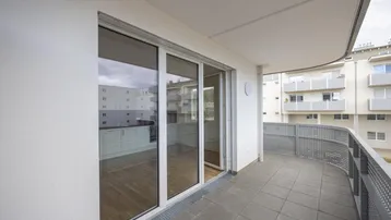 Geräumiger Balkon mit Fliesenboden und Blick auf die umliegenden Gebäude des Neubaus.