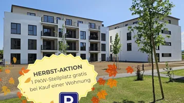 Modernes Mehrfamilienhaus mit weißer Fassade, Balkonen und gepflegter Grünanlage im Freien.