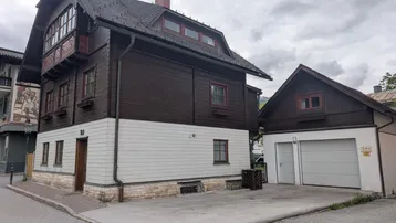 Traditionelles Haus mit dunkler Holzfassade und heller Verkleidung, inklusive Garage.