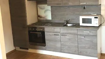 Moderne Einbauküche mit grauen Holzfronten, integrierten Geräten und praktischem Stauraum.