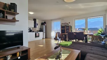 Offener Wohnbereich mit integrierter Küche, Essbereich und Zugang zum Balkon.
