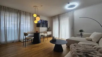 Moderner Wohn-Essbereich mit Holzboden, bequemer Couch und stilvoller Beleuchtung, ideal für entspannte Abende.