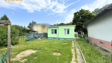 Grüner Gartenbereich mit einem kleinen Gebäude und einem Pfad unter bewölktem Himmel.