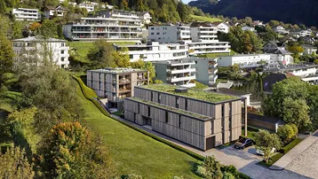 Moderne Gebäude mit begrünten Flachdächern, eingebettet in eine grüne Hügellandschaft.