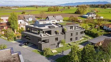 Moderne Wohnanlage mit Flachdach, Gründach und Solaranlagen in ländlicher Umgebung.