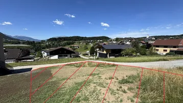 Unbebautes Grundstück mit markierten Parzellen und weitem Blick auf die umliegende Landschaft und Berge.