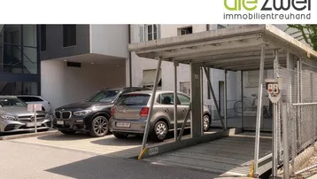 Modernes Parksystem mit Hebebühne und mehreren Stellplätzen vor einem Gebäude.