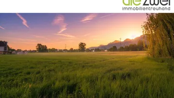 Weitläufiges Feld mit malerischem Sonnenuntergang und Bergpanorama im Hintergrund.