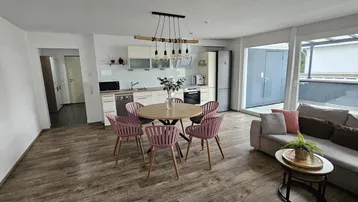 Offener Wohn-Essbereich mit integrierter Küche, Holzboden und Zugang zur Terrasse.