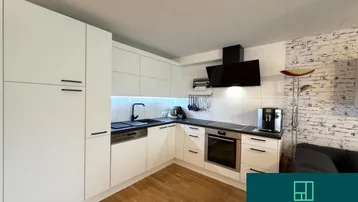 Moderne weiße Einbauküche mit dunkler Arbeitsplatte, integrierten Geräten und Holzfußboden.
