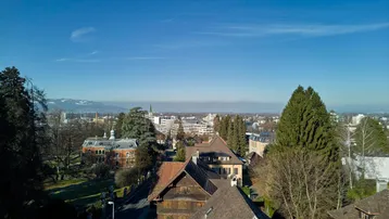 Weitläufige Luftaufnahme einer Wohngegend mit Blick auf die Stadt und ferne Berge unter blauem Himmel.