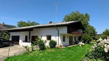 Traditionelles Einfamilienhaus mit weißer Fassade, Garage und gepflegtem Vorgarten.