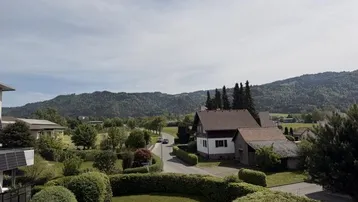 Weitläufiger Blick über die Nachbarschaft und grüne Hügel mit bewaldeten Bergen im Hintergrund.