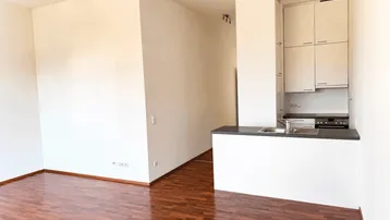 Heller Wohnbereich mit integrierter Küchenzeile und warmem Holzfußboden, ideal für offenes Wohnen.