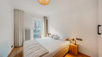 Gemütliches Schlafzimmer mit Doppelbett, Holzboden und direktem Zugang zum Balkon.