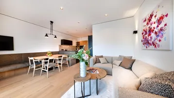Moderner offener Wohn- und Essbereich mit Holzboden, bequemer Couch und stilvoller Dekoration.