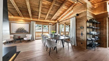 Geräumiger Essbereich mit Holzbalkendecke, großen Fenstern und Zugang zu einem Balkon.