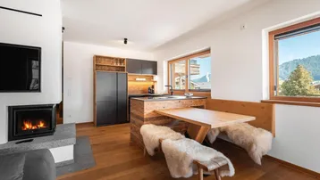 Moderne Küche mit Holzelementen, Essbereich und Bergblick durch große Fenster.