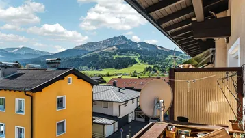 Panoramablick vom Balkon auf die majestätischen Berge und die grüne Landschaft unter blauem Himmel.