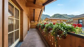 Geräumiger Holzbalkon mit bunten Blumenkästen und herrlichem Blick auf die umliegende Berglandschaft.