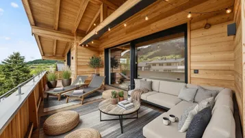 Geräumiger Balkon mit Holzelementen, bequemen Lounge-Möbeln und malerischem Bergblick.