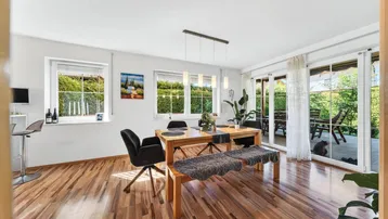 Helles Esszimmer mit Holzboden, großem Esstisch und direktem Zugang zur Terrasse und zum Garten.