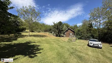 Großer Garten mit weitläufiger Rasenfläche und einem kleinen Holzhaus im Hintergrund.