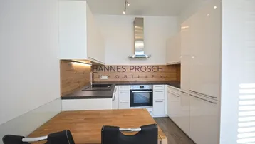 Moderne Küche mit weißen Hochglanzfronten, Holzakzenten und integrierten Geräten.