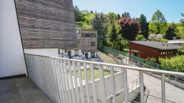 Geräumiger Balkon mit Metallgeländer und weitem Blick über die grüne Landschaft.