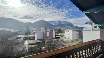 Panoramablick vom Balkon auf die umliegende Berglandschaft und Gebäude.