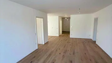 Geräumiger, heller Wohnbereich mit neuem Holzboden und weiß gestrichenen Wänden, bereit zum Einzug.