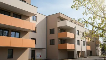 Moderne Wohnanlage mit mehreren Balkonen und heller Fassade unter blauem Himmel.