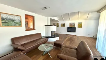 Geräumiges Wohnzimmer mit Ledersofas, modernem Kamin, Holzboden und Dachschrägen mit Oberlichtern.