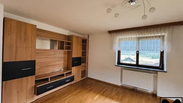 Helles Wohnzimmer mit moderner Holz-Wohnwand und großem Fenster mit Panoramablick.