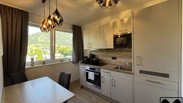 Moderne Wohnküche mit Essbereich, Einbauküche und Blick auf die umliegende Berglandschaft.