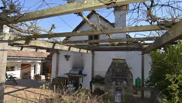 Gemütliche Außenterrasse mit Pergola, Grillbereich und rustikalem Steinofen für gesellige Stunden im Freien.