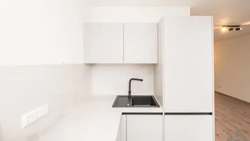 Moderne Küche mit hellgrauen Schränken, schwarzer Spüle und Armatur, sowie Holzboden im Hintergrund.