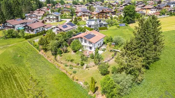 Luftaufnahme eines Einfamilienhauses mit Photovoltaikanlage und großem Garten in ländlicher Umgebung.