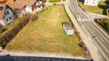 Luftaufnahme eines unbebauten Grundstücks mit einem kleinen Schuppen und angrenzender Straße.