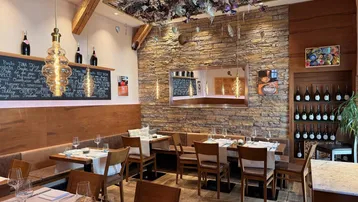 Gemütlicher Essbereich mit rustikaler Steinwand, Holzbalken und eleganten Holztischen.