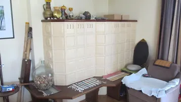 Traditioneller Kachelofen in einem Wohnbereich mit Holzboden, der Wärme und Gemütlichkeit spendet.