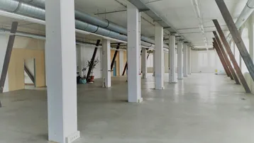 Großer, offener Gewerberaum mit vielen Säulen, sichtbaren Lüftungsrohren und Betonboden, ideal für flexible Nutzung.