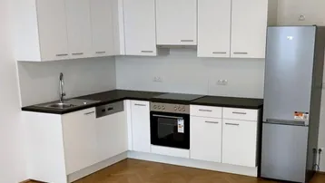 Moderne Einbauküche in Weiß mit dunkler Arbeitsplatte, Herd und Kühlschrank.