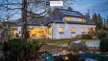 Elegantes Landhaus mit weißer Fassade, großem Garten und Teich in idyllischer Umgebung.