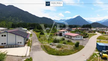Luftaufnahme eines Grundstücks in ländlicher Umgebung mit Bergblick und umliegenden Gebäuden.