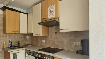 Funktionale Küche mit hellen Holzschränken, Fliesenrückwand und Laminatboden, ausgestattet mit modernen Geräten.