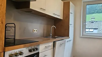Helle Einbauküche mit Holztheke, modernen Geräten und Blick ins Grüne.