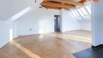 Heller, offener Dachgeschossraum mit Fischgrätparkett, sichtbaren Holzbalken und Dachfenstern.